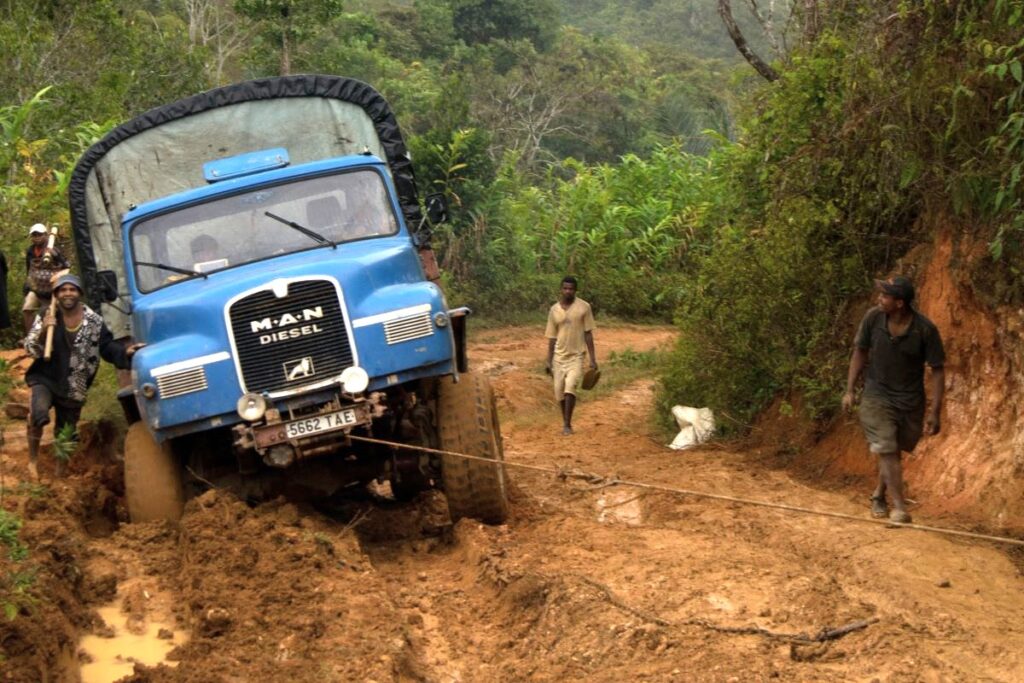 Ein großer Diesel-Lkw steckt auf einem schmalen Waldweg im tiefen Schlamm fest.