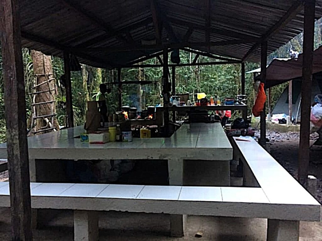 Image of white tiled table and benches under a covered shelter with open sides.