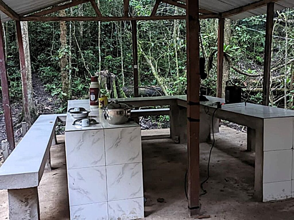 Image of white tiled table and benches under a covered shelter with open sides.