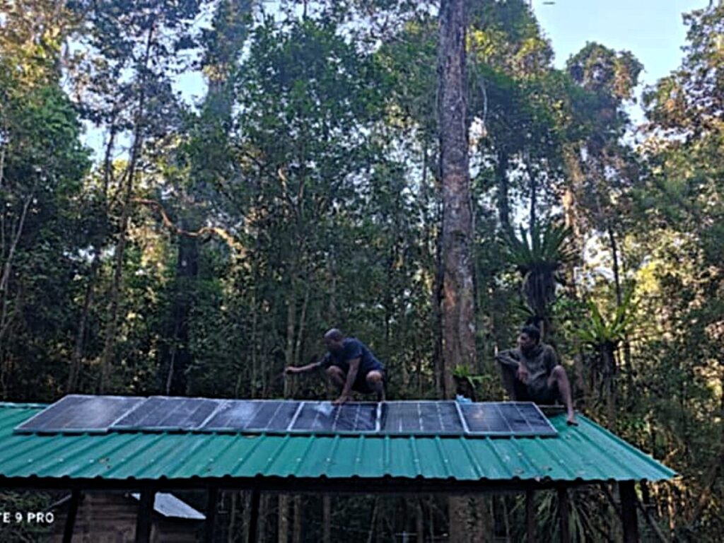 Image of two men installing solar panels on a green metal roof.