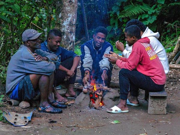Image représentant cinq hommes assis autour d'un petit feu de camp.